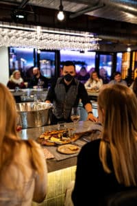 Bartender serving drinks in open restaurant with many guests