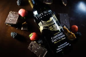 Bottle of wine and chocolate on dark wood table. 