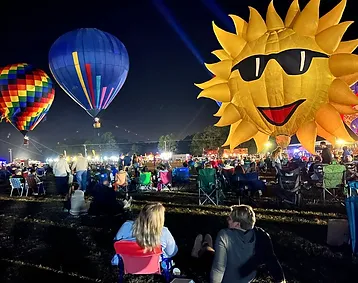 Multiple hot air balloons at night.