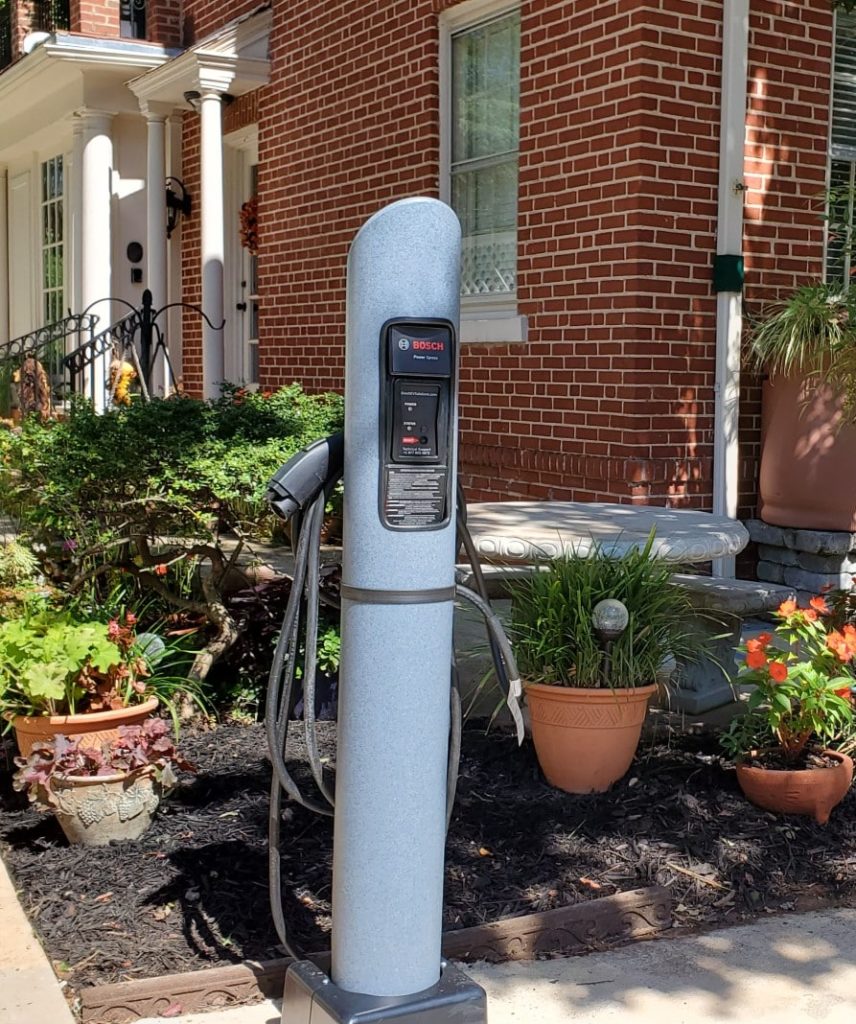 Electric vehical charger in corner of parking lot.