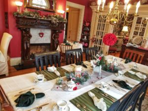Dining room with multiple tables, fireplace, and mantel decorated for Valentine's day.