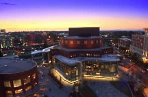 City skyline at dusk featuring a modern theater building in Greenville, NC.