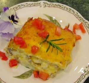 Cheese covered pasta noodles on fine white china with diced tomatoes 