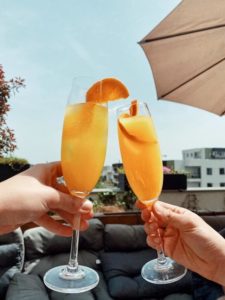 Two hands toasting Mimosas