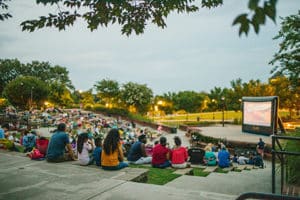 Many people seated outside enjoying a movie.