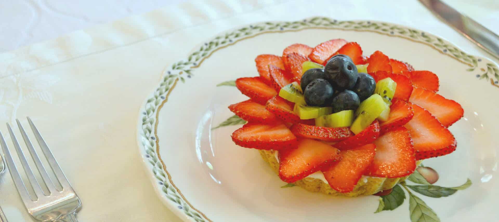 Fruit tart with strawberries, kiwi and blueberries on a china plate.