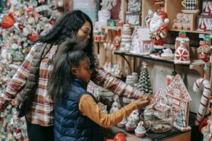 happy-black-mother-with-daughter-choosing-souvenirs-in-shop
