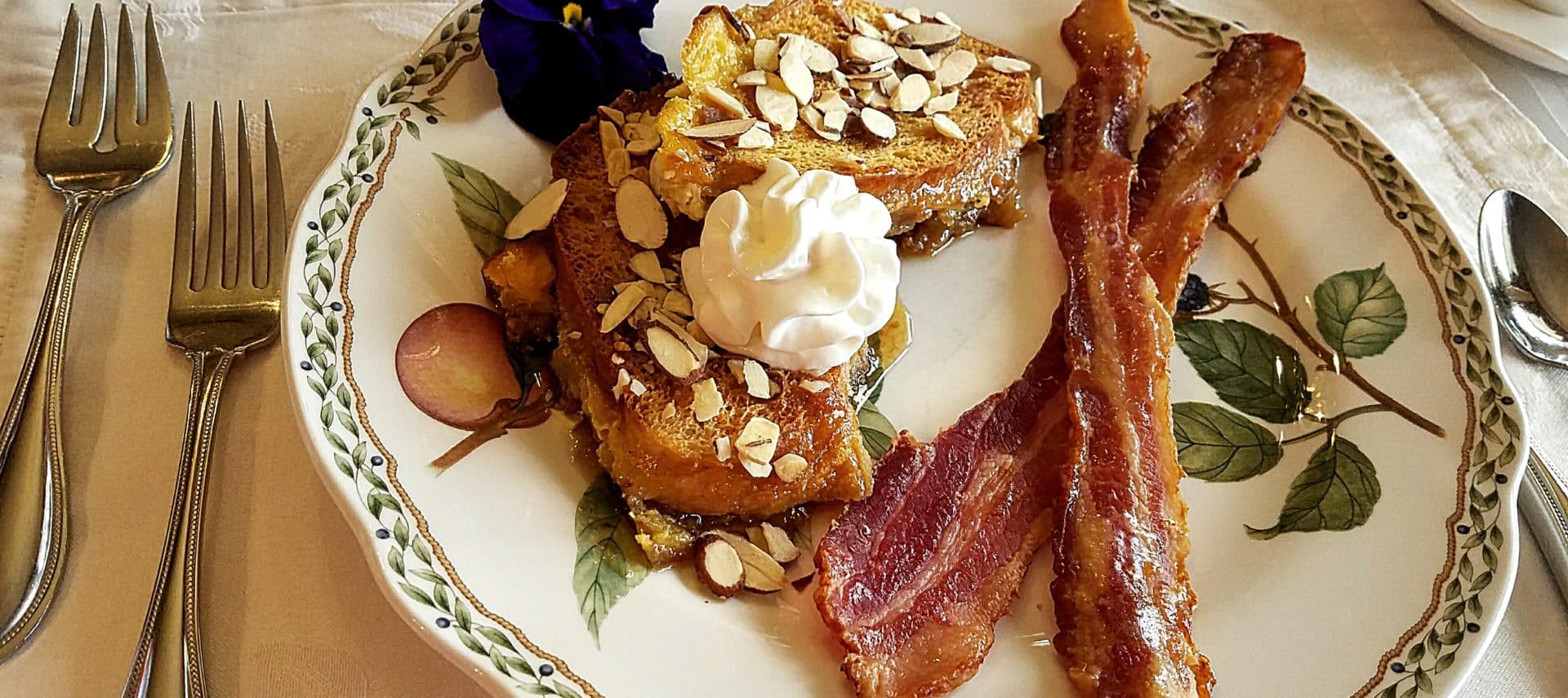 Beautiful china place setting with almond topped French Toast and bacon.