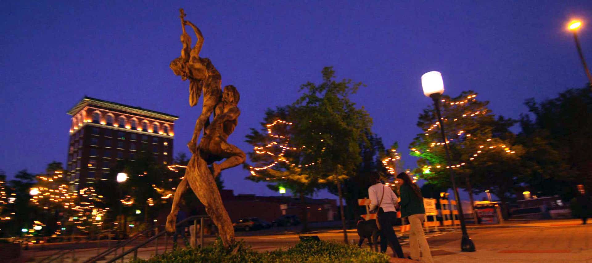 Stone statue on main street at night