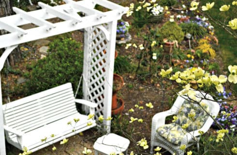 Pretty garden seating area with a white arbor swing and wicker furniture.