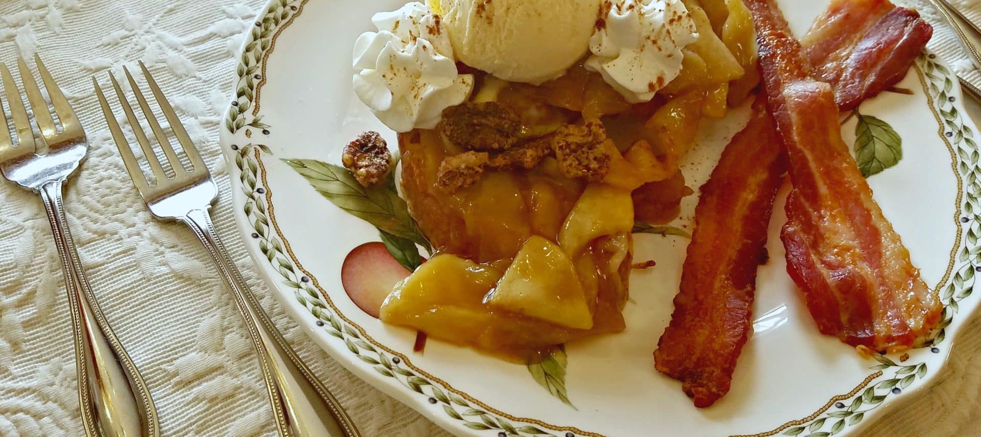 French toast with two pieces of bacon with candied pecans and ice cream on fine china.