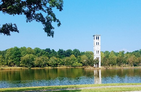 Large white tower building fronted by a calm body of water on a sunny day.