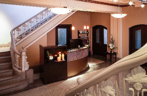 Elegant lobby with grand staircases on either side and an art deco-style front desk.