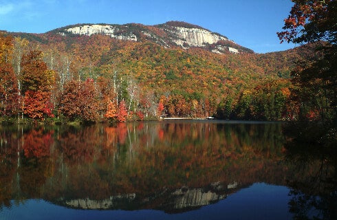 Beautiful view of tall mountain fronted by atumn foliage and a placid lake.