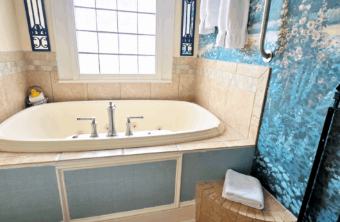 Large two person jetted tub in bathroom with garden mural.