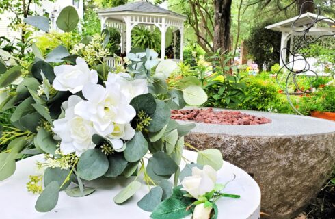 Bouquet of white flowers in garden in front of gazebo.