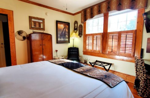 Leather chair with antique armoire near windows