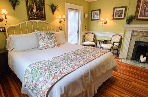 California King bed with candle lit fireplace and two chairs