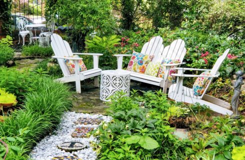 Adirondack chairs in english garden with chipped marble stone pathway.