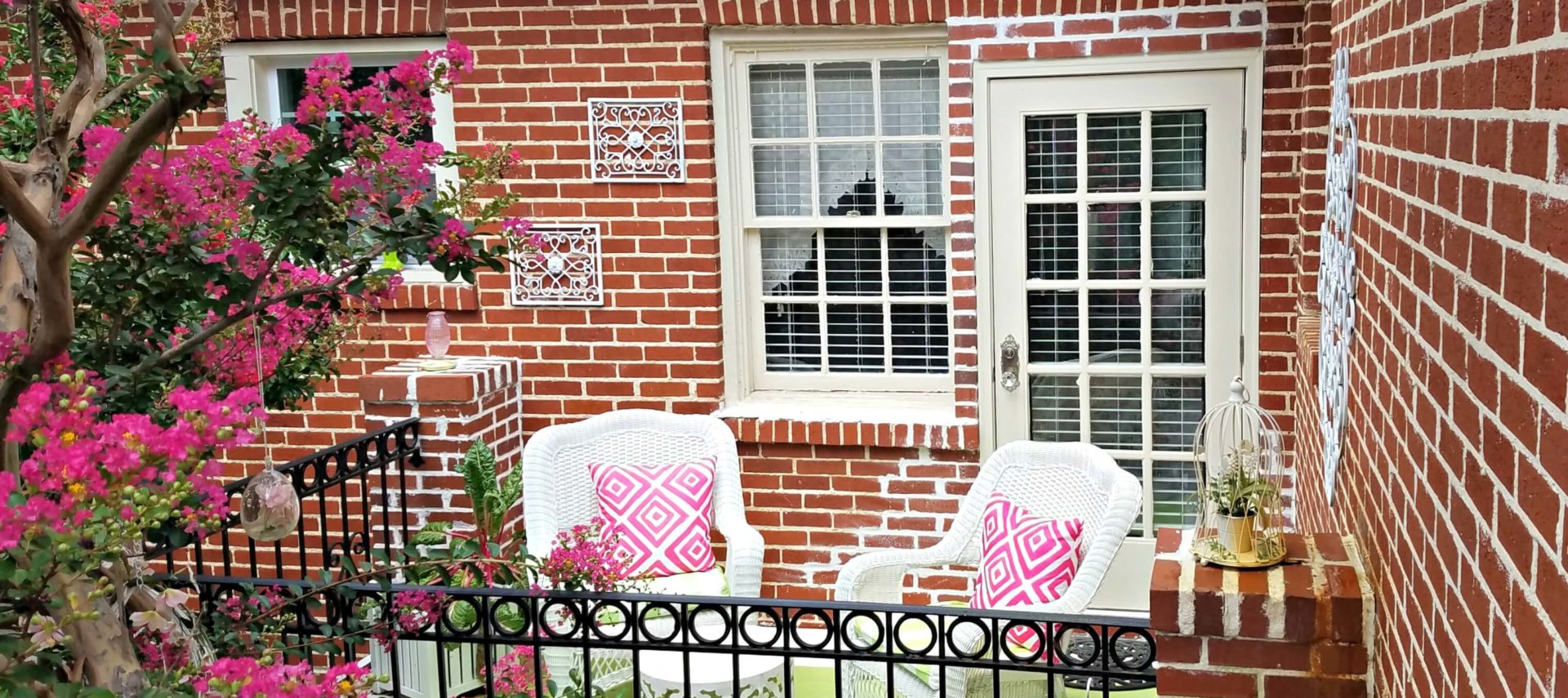 Private patio with white wicker furniture with pink and green accents.