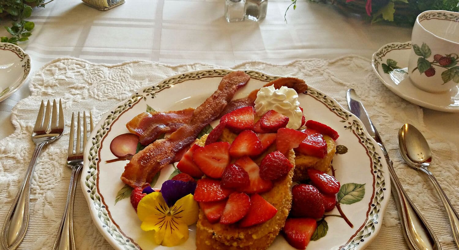 Lemonade french toast topped with sliced strawberries and whipped cream on a china plate. 