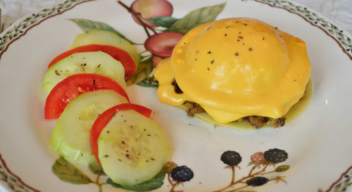 Eggs benedict accompanied by tomato and cucumber on a china plate. 