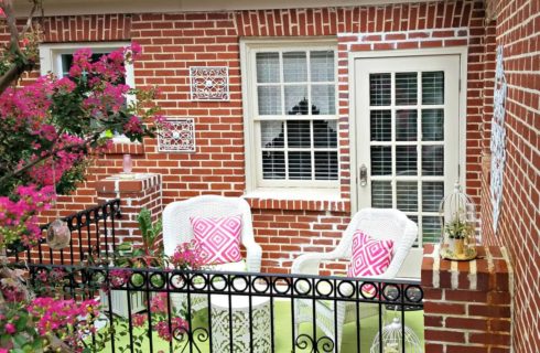 Private patio with white wicker furniture with pink and green accents.