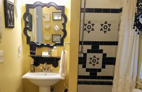 Bathroom decorated in gold and balck with a shower and vanity sink.