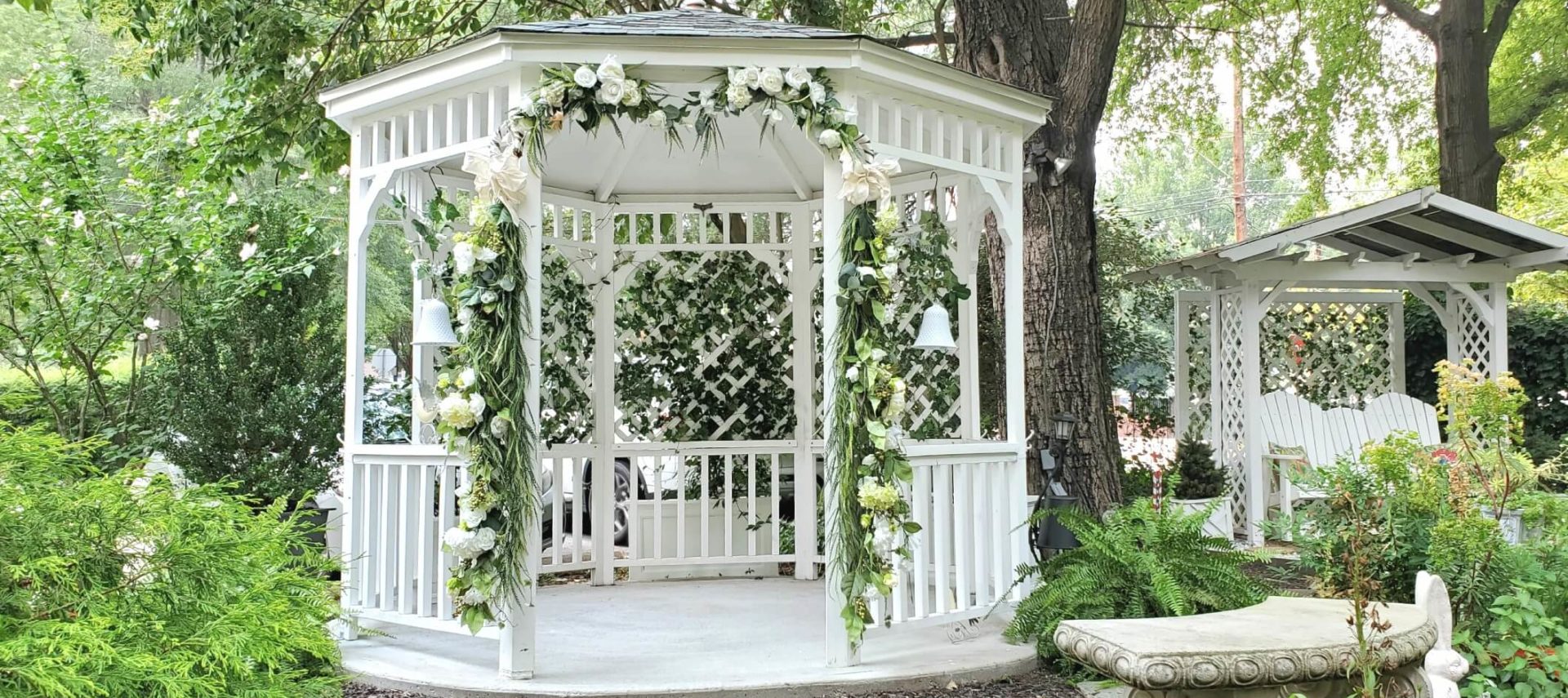 Floral decorated white gazebo and glider in garden.