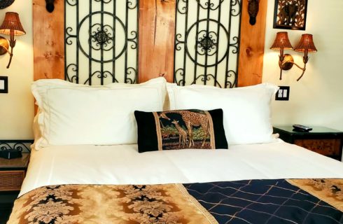 California King bed with giraffe pillow by two bedside tables and lamps