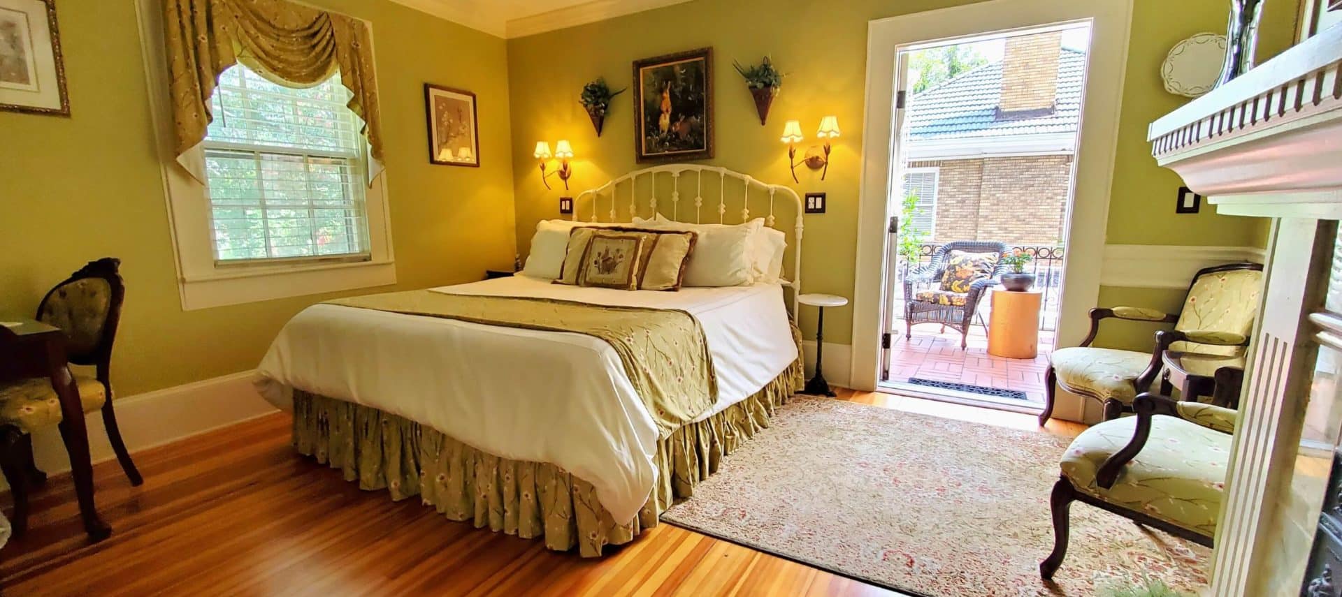 California king bed in room with open door to private balcony with chair.