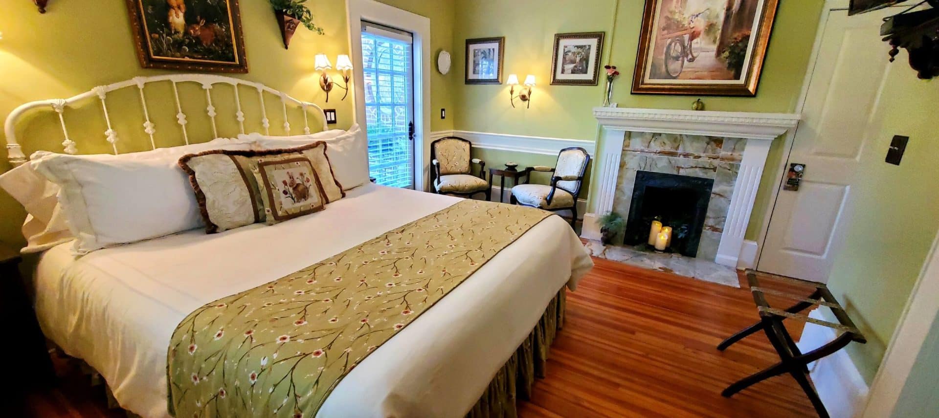 California king bed near two chairs and candle lit fireplace.