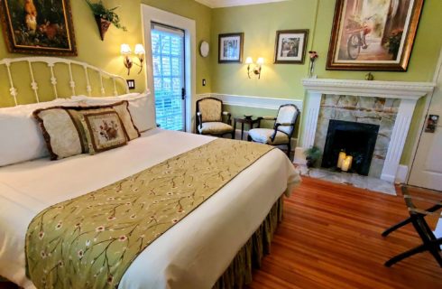 California king bed near two chairs and candle lit fireplace.