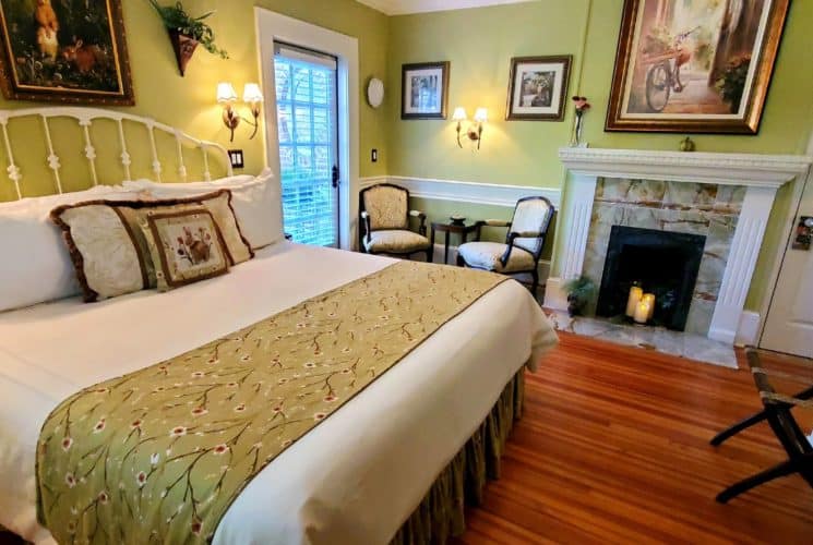 California king bed near two chairs and candle lit fireplace.