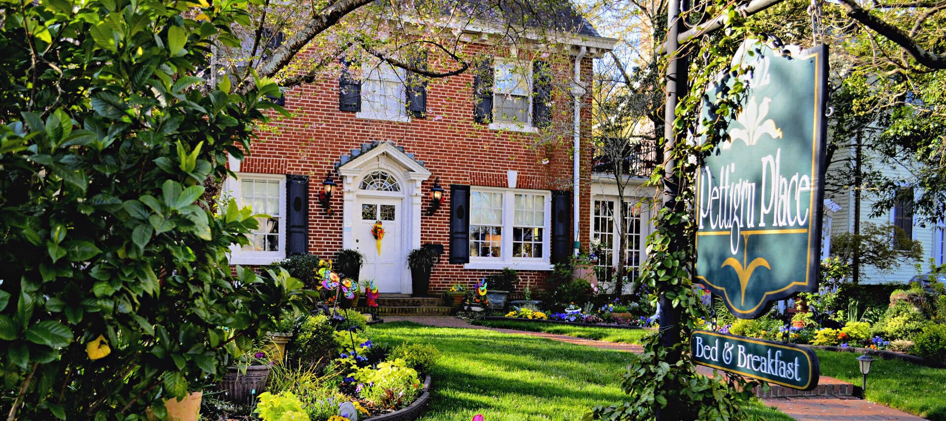 Brick colonial-style home with black shutter and roof and white door and windows.