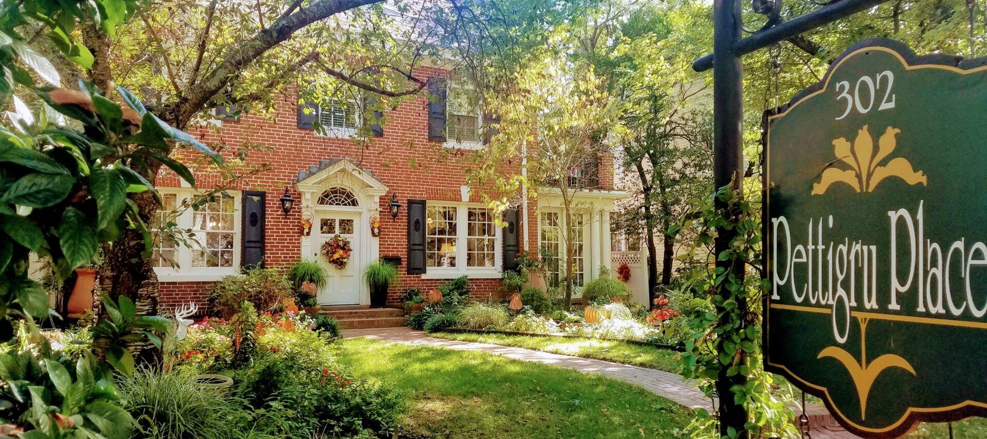 Front view of red brick Colonial home with lots of white windows and sign with text Pettigru Place