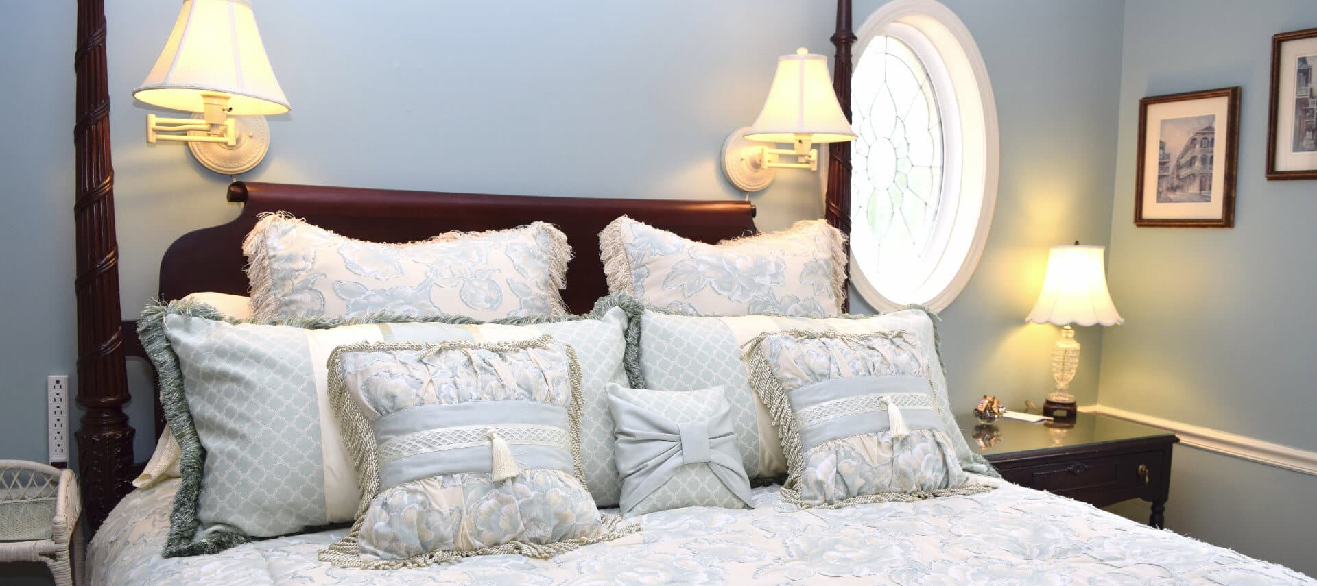 Large four-poster bed made up in white with many decorative pillows.
