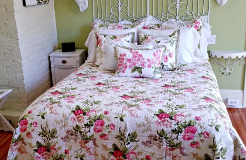 white wrought iron bed with floral bedding and night stand