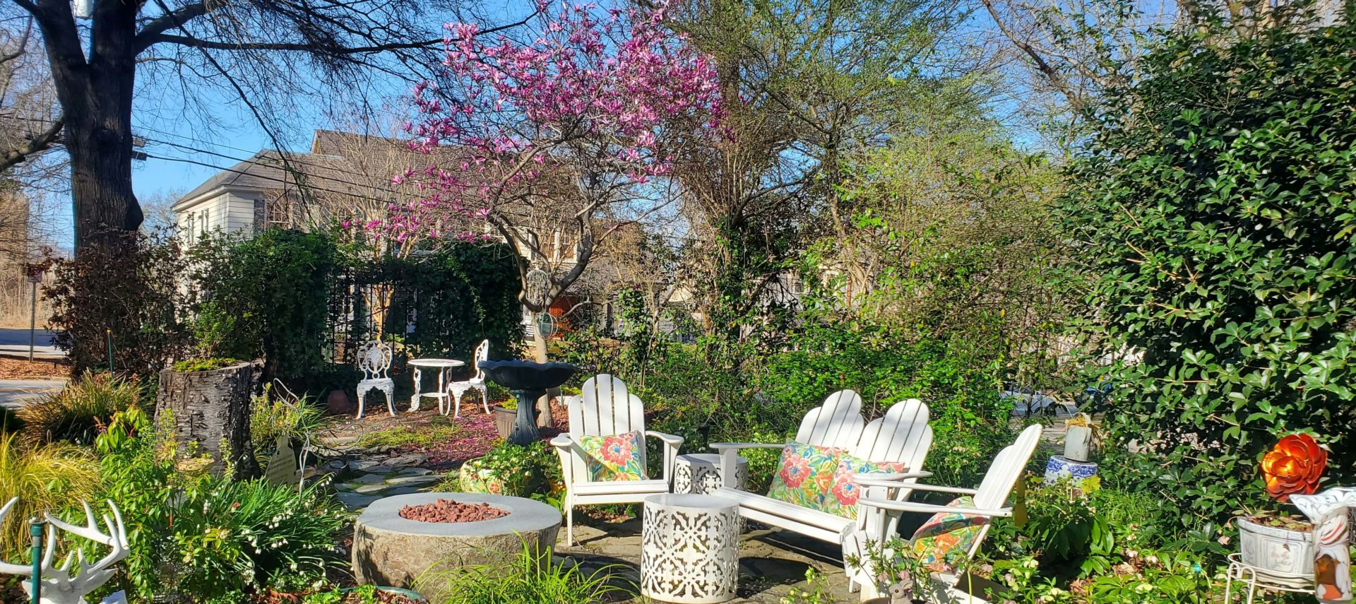 Adirondack chairs by fire pit on spring day in the garden.