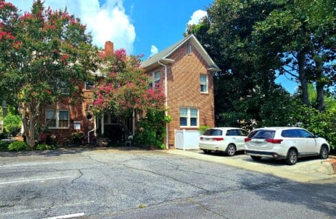 Parking lot of red brick building with blooming crepe myrtle trees.