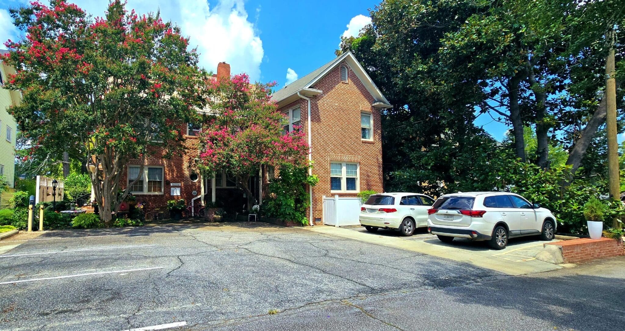 Parking lot of red brick building with blooming crepe myrtle trees.