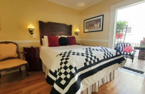 Queen bed with antique headboard and chair open balcony door.