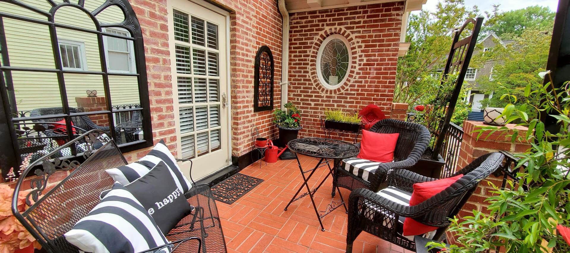 Red brick balcony with black wicker seating and pillows