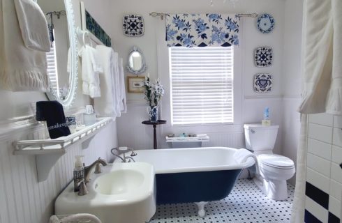 Antique claw foot tub painted dark blue in beautiful white bathroom