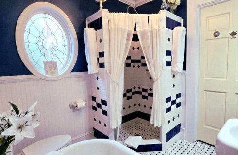 curtained shower with blue and white tiled shower in bathroom with blue walls.