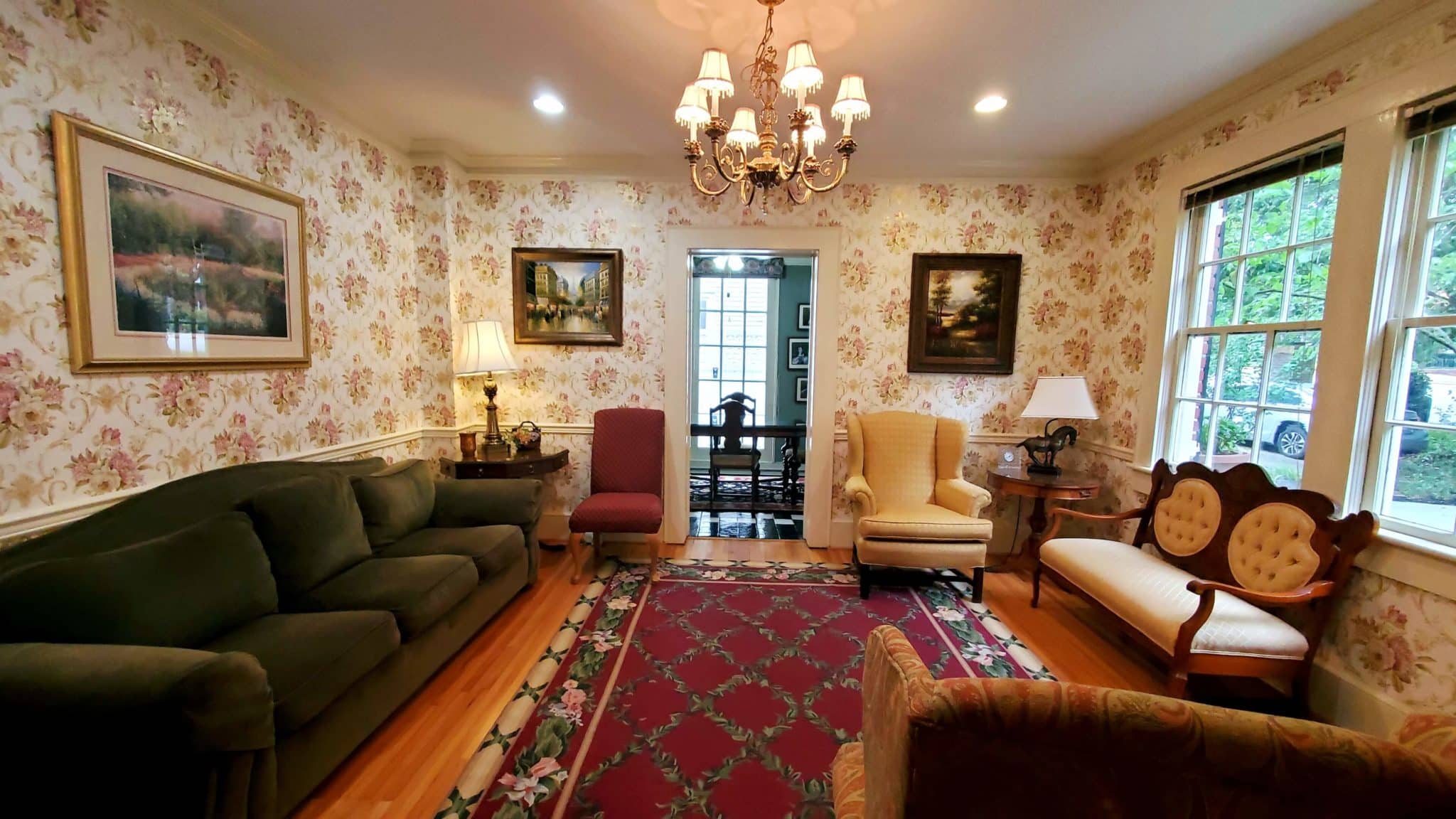 Elegant sitting room with green couch and chairs with view of the garden.