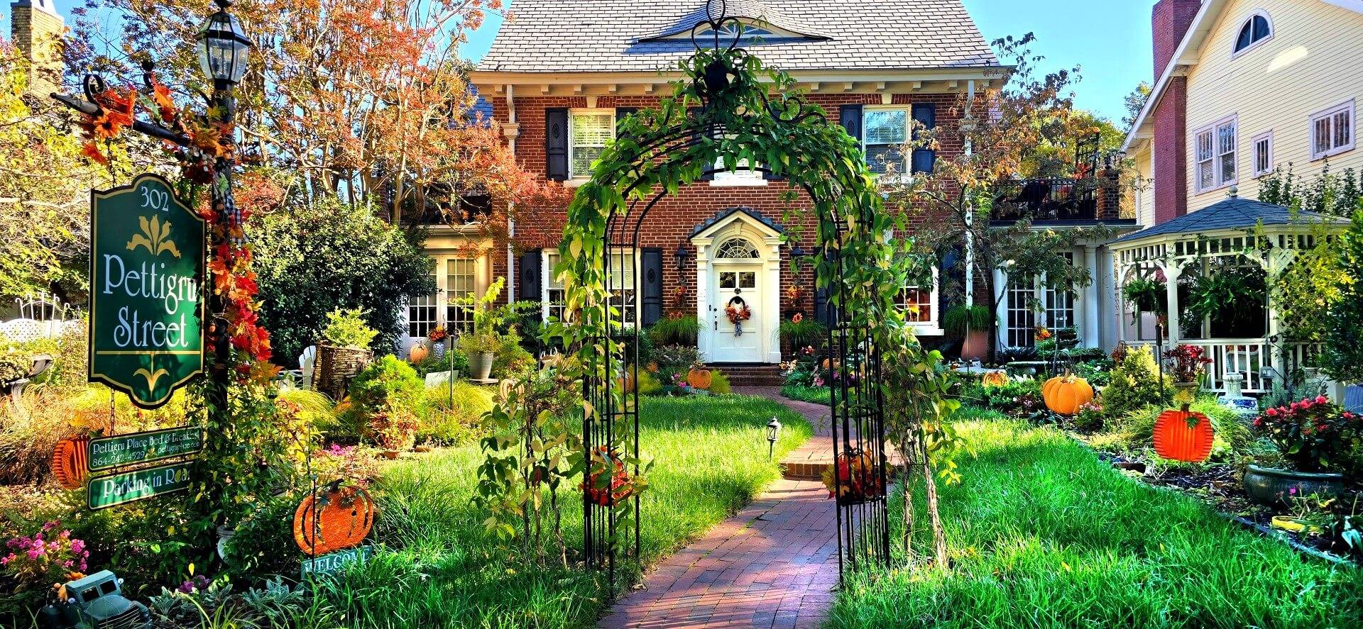 Front of two story brick house with fall decorated garden