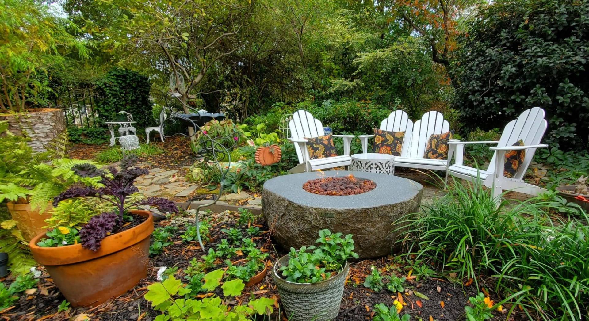 Lit fire table in blooming garden with chairs
