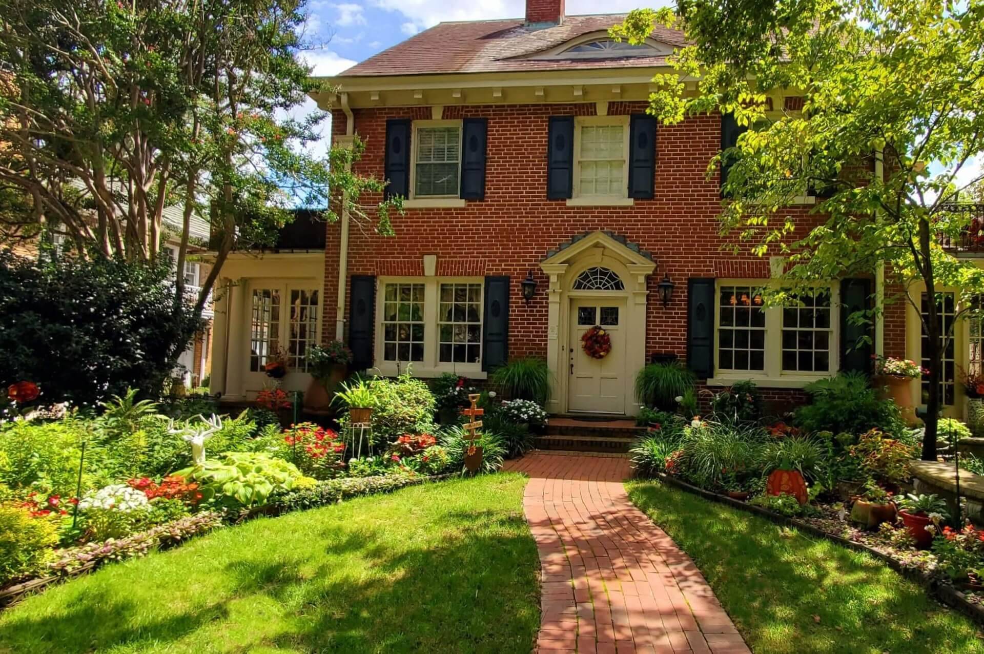 two story red brick inn with lush fall garden