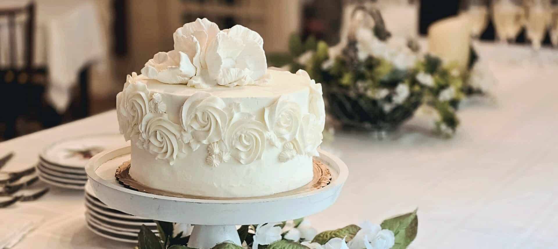White wedding cake with floral background and champagne glasse